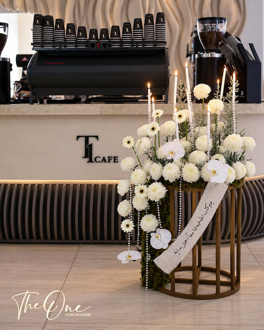 Luxury white flower arrangement with orchids, chrysanthemums, candles and pearl details on a gold stand by The One Flowers UAE