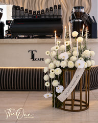 Luxury white flower arrangement with orchids, chrysanthemums, candles and pearl details on a gold stand by The One Flowers UAE