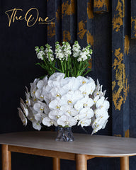 Luxury white Phalaenopsis orchid arrangement with white stock flowers in a glass vase by The One Flowers UAE