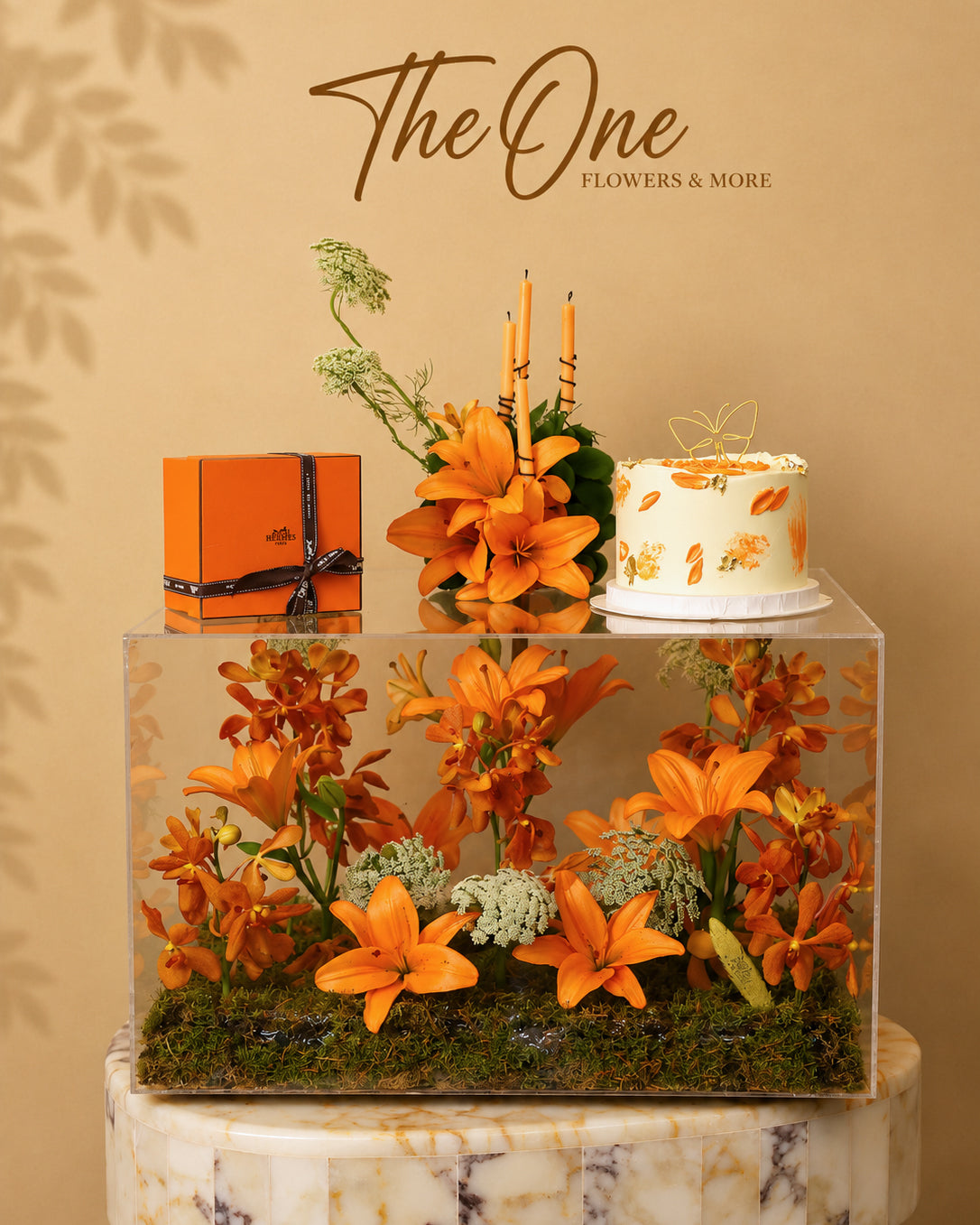 Luxury orange flower and cake arrangement with lilies and orchids in an acrylic display by The One Flowers UAE